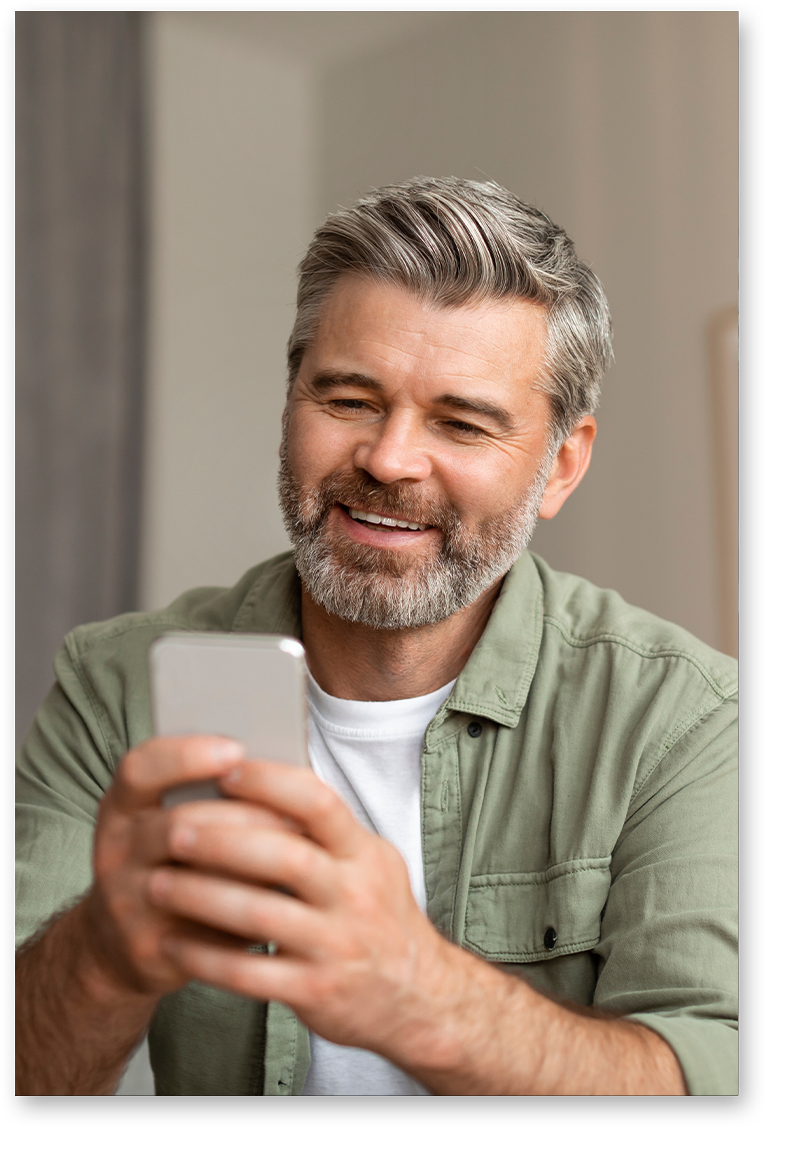 Smiling man with dentures looking at phone