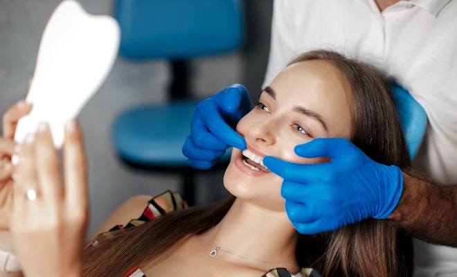 Woman looking at smile in mirror at the dentist